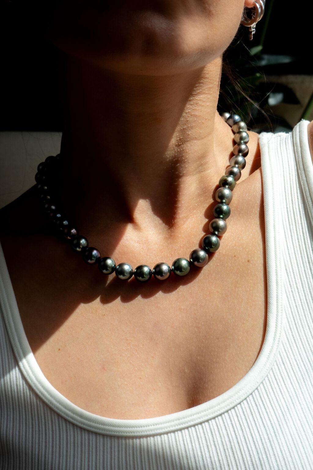 Woman in white tank top wearing silver-colored Tahitian pearls